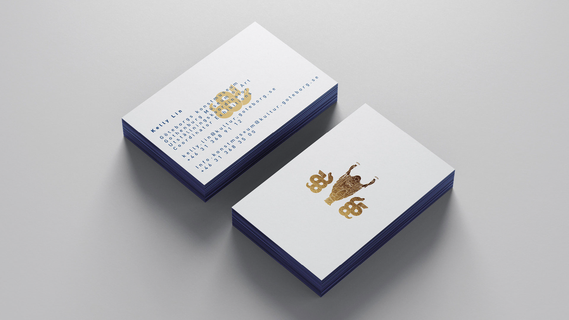 Image of Two stacks of business cards. The business card on the left has blue text on white with a gold dragon underneath. The business card on the right has a white background and golde logo ontop. Designs made with Adobe illustrator and Adobe Indesign